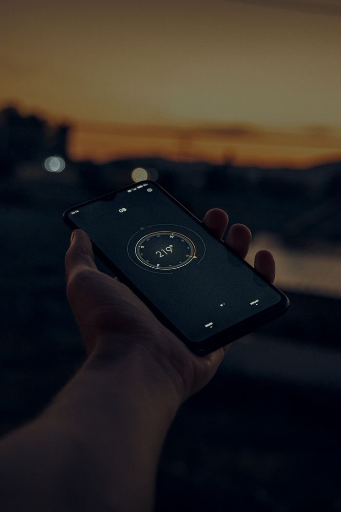 Mastering the First Impression: Your intriguing post title goes here A person holding a smartphone displaying a compass app at sunset.