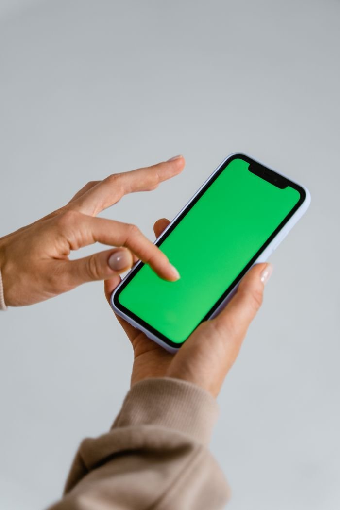 Crafting Captivating Headlines: Your awesome post title goes here A person interacting with a smartphone displaying a green screen, ideal for design mockups.